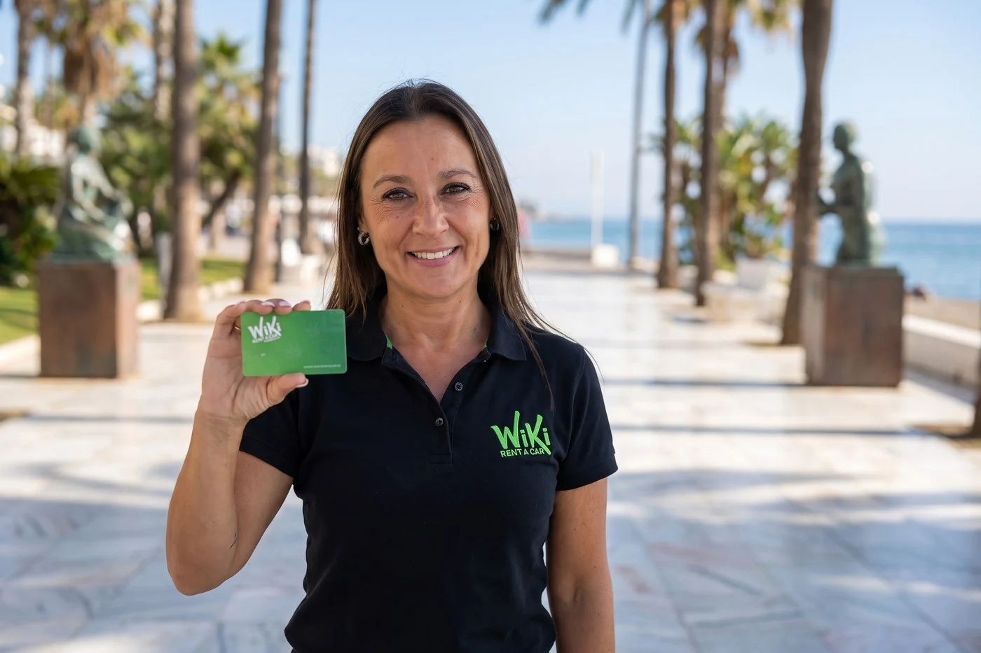 Empleada de Wiki Rent A Car con la tarjeta de cliente en el paseo marítimo de Marbella, punto de recogida del coche de alquiler